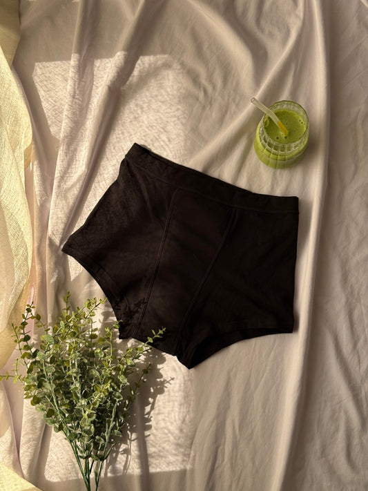 Image d'une culotte menstruelle nuit sur un drap blanc avec un matcha et une branche en décoration.