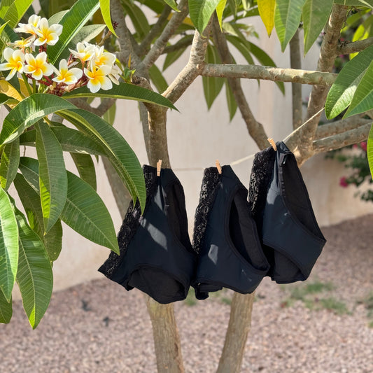 Photo montrant trois culottes menstruelles dentelles suspendues sur un fil à linge à l'extérieur illustrant le coffret dentelle.