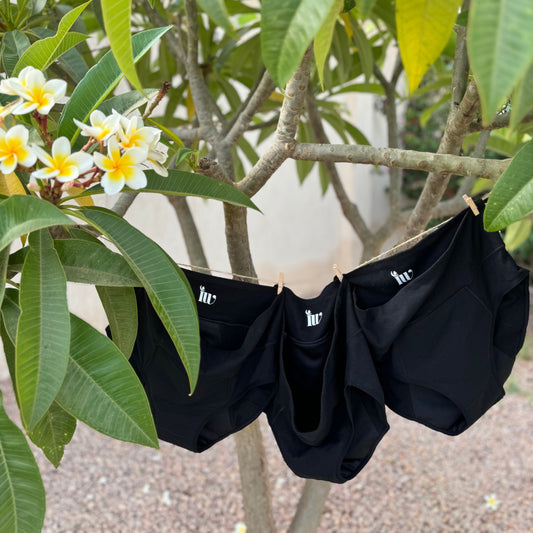 Photo montrant trois culottes menstruelles taille haute suspendues sur un fil à linge à l'extérieur, illustrant le coffret taille haute.