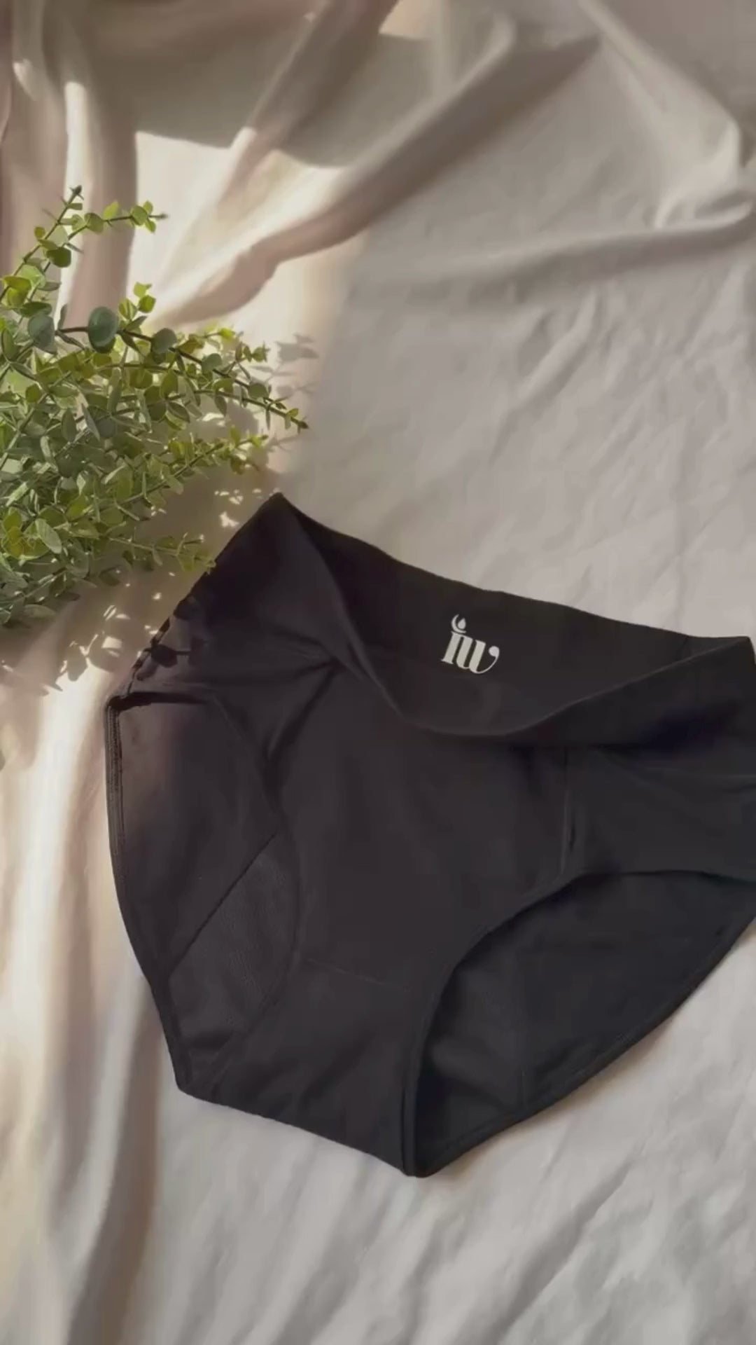 Vidéo zoomant lentement sur le modèle taille haute, présenté sur un drap blanc et décoré d'une branche.