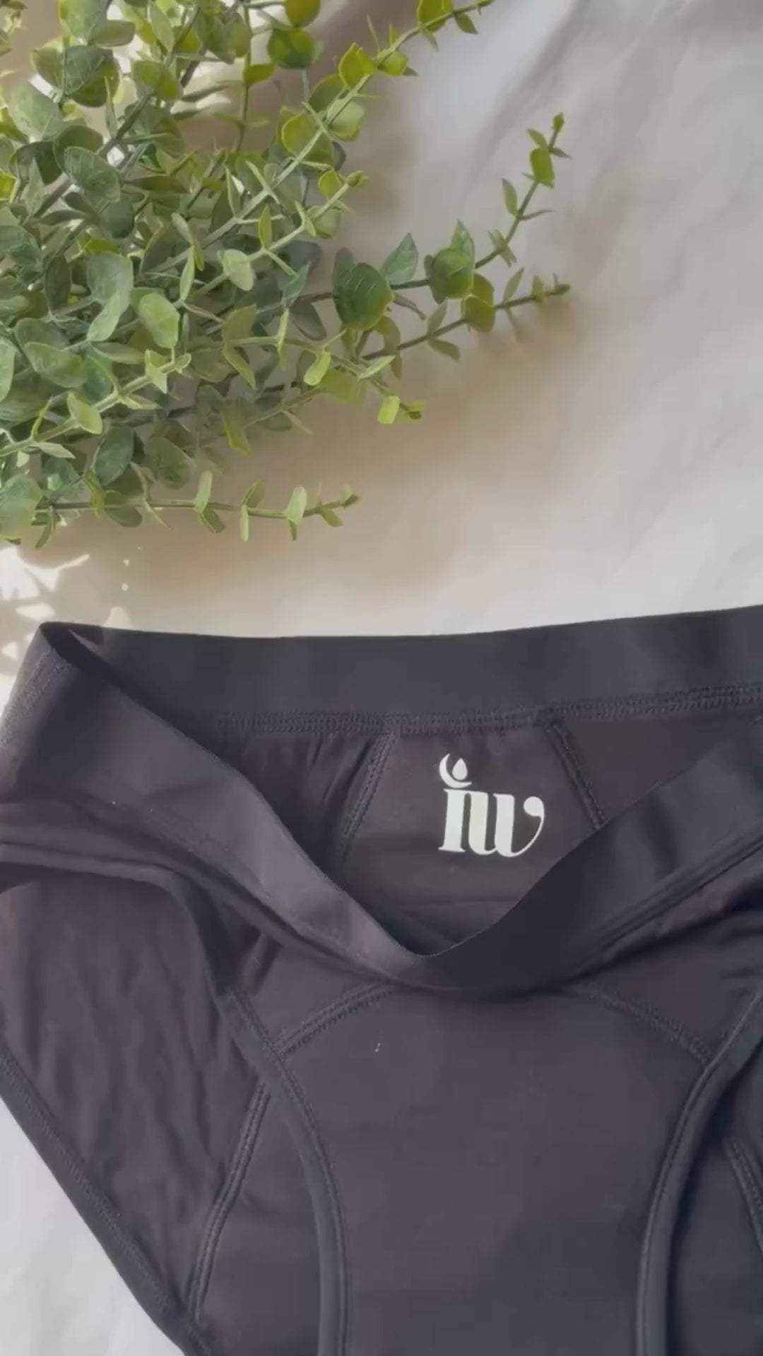 Vidéo montrant la culotte menstruelle modèle standard, de face, avec l'encolure pliée et des branches décorant le haut de la vidéo.